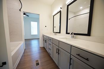 A bathroom with a sink, mirror, and wooden floor at Wesley Place Apartments in Birmingham, AL